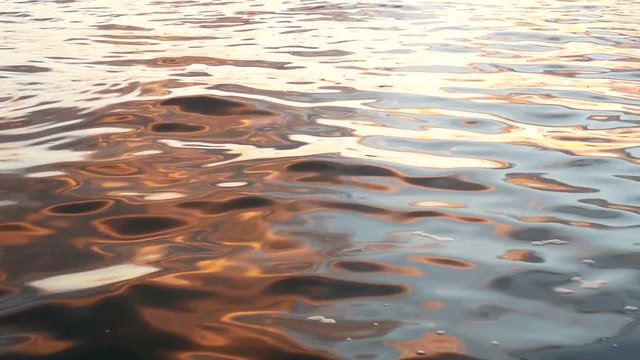 Water surface background Slow Motion. Calm water waves at golden hour