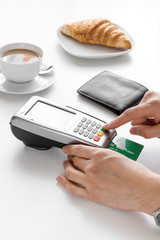 Croissant and coffee on white table payment by card in cafe