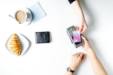 Croissant and coffee payment by card in cafe top view