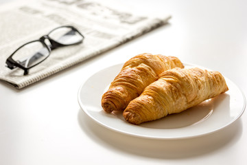 Breakfast for businessman with newspaper and croissant on white table