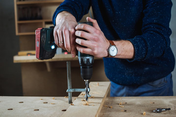 Young man piercing a hole through a wooden plank