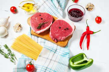 Raw beef steak with pasta, tomatoes, mushrooms and cheese on white table background