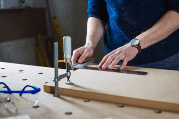 Young man working as carpenter and measuring board
