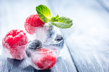 cubes of berry ice and mint leaf on wooden table beckground
