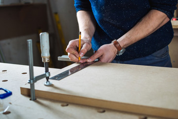 Young man working as carpenter and measuring board