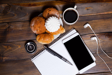 Camera lens with croissants and coffee next to notebook