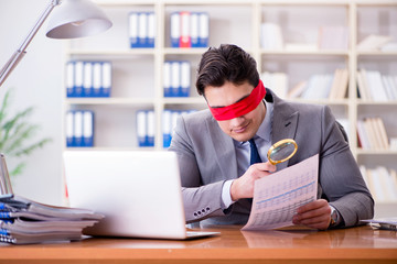 Blindfold businessman sitting at desk in office