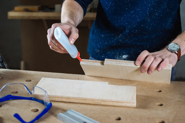 Young man working as carpenter and measuring board