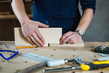 Young man working as carpenter and measuring board