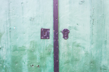 Green wooden door close up detail with rusty lock
