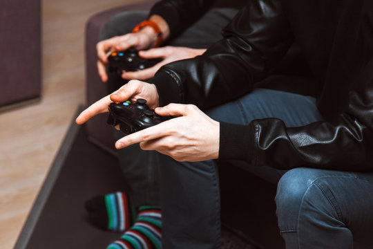 Close up men with joysticks in hand playing computer video game at home. The concept of friendship, technology and weekend