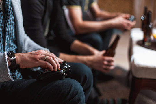 Close up men at home with a beer and chips with joysticks in hand playing computer video game. The concept of friendship, technology and weekend