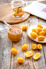 kumquat on plate and jam in jar at wooden table