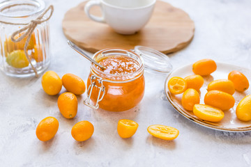 kumquat on plate and jam in jar at gray background
