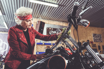 Thoughtful pensioner polishing bike in mechanic shop