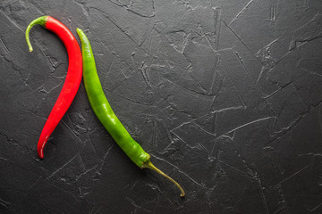 Red and green chili pepper on a black stone