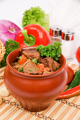 Beef with vegetables in wine sauce, stewed in a clay pot, decorated with parsley