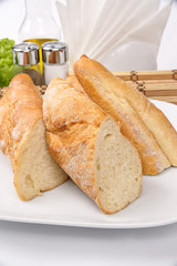Homemade bread baguette on a white plate decorated with lettuce