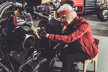 Fototapeta na wymiar Cool retire cleaning motorcycle in mechanic shop