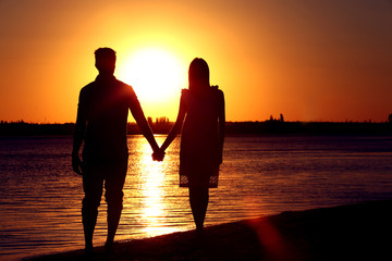 Young couple in love on summer sunset beach