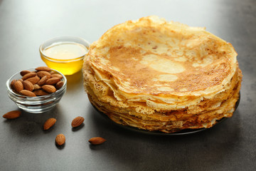 Plate with delicious pancakes, almonds and honey on table