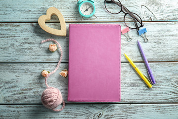 Pink notebook and stationery on wooden background