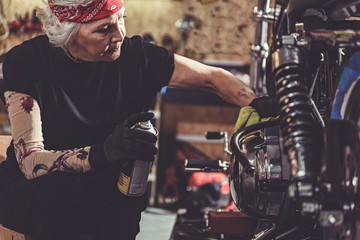 Serene female retiree polishing motorcycle in garage