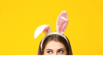 Beautiful young woman with bunny ears and blank poster on color background