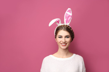 Beautiful young woman with bunny ears on color background