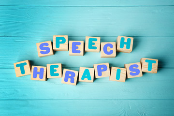 Cubes with text SPEECH THERAPIST on blue wooden background