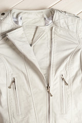 White leather jacket on white background. Leather jacket macro details. Jacket zippers and pockets