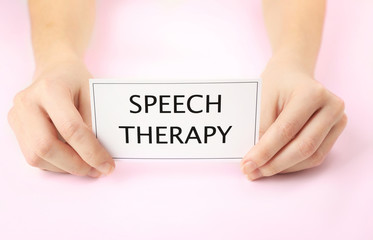 Speech therapy concept. Hands holding card on light background