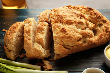 Wooden board with tasty loaf of beer bread on table