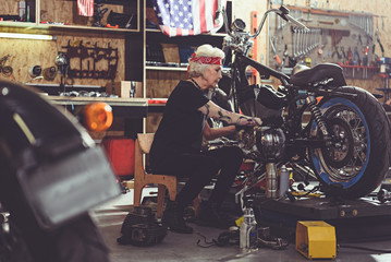 Serene grandmother repairing bike in mechanic shop