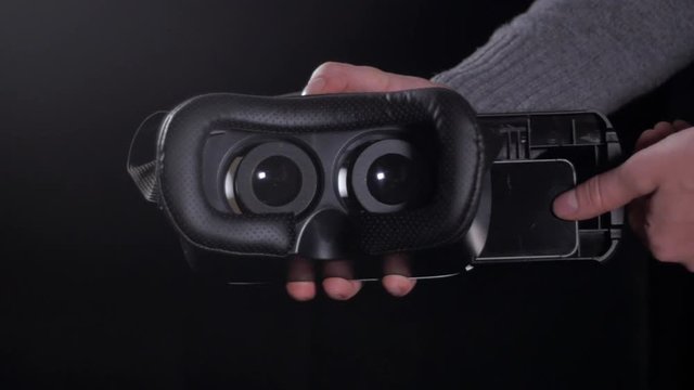 VR virtual reality glasses with phone putting inside, close up on dark background.