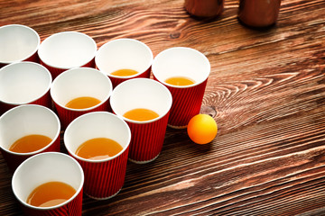 Plastic beer pong cups and ball on wooden table