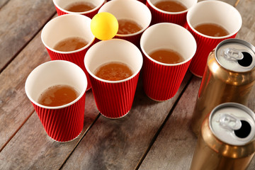 Plastic beer pong cups and ball on wooden table