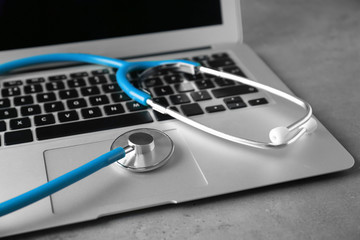 Modern laptop and stethoscope on table