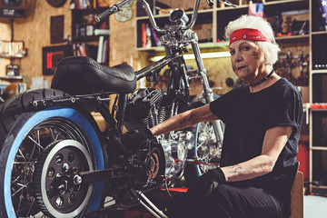 Fototapeta na wymiar Serious retiree repairing bike in mechanic shop