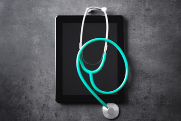 Stethoscope and tablet pc on grey table