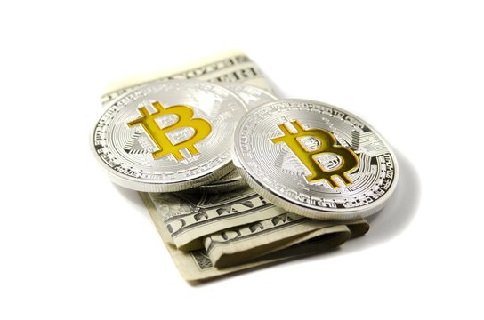 Shiny silver and gold Bitcoin coins and US dollars on white background