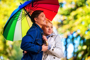 Autumn couple walking park. Fall friends walk under rain umbrella. First date of two young people in rainy day.
