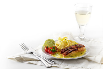 Salmon dish with saffron sauce and tagliatelle pasta, lime slice, cherry tomatoes, dill garnish and wine, bright corner background fades to white