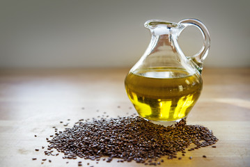 flax seeds and linseed oil in a glass jug on a wooden kitchen board, healthy diet with omega 3...