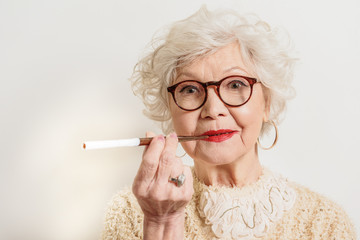 Happy old woman enjoying tobacco pipe