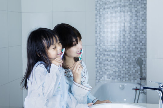 Mother And Child Brushing Teeth Together