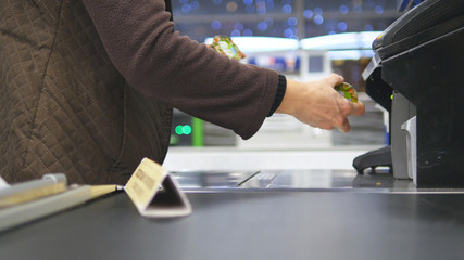 Shopper paying for products at checkout. Foods on conveyor belt at the supermarket. Cash desk with cashier and terminal in hypermarket. Working of cashier. Shopping at store. Close up