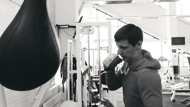 Slow motion of young boxer man practicing on a punching bag in sport fitness club