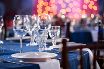Wedding. Banquet. The chairs and round table for guests, served with cutlery and crockery and covered with a blue tablecloth.