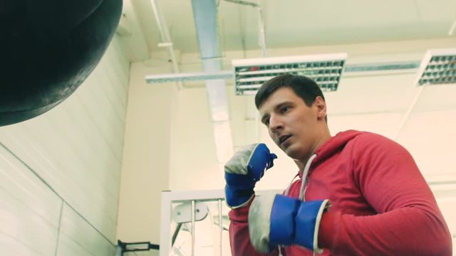 Slow motion of young boxer man practicing on a punching bag in sport fitness club